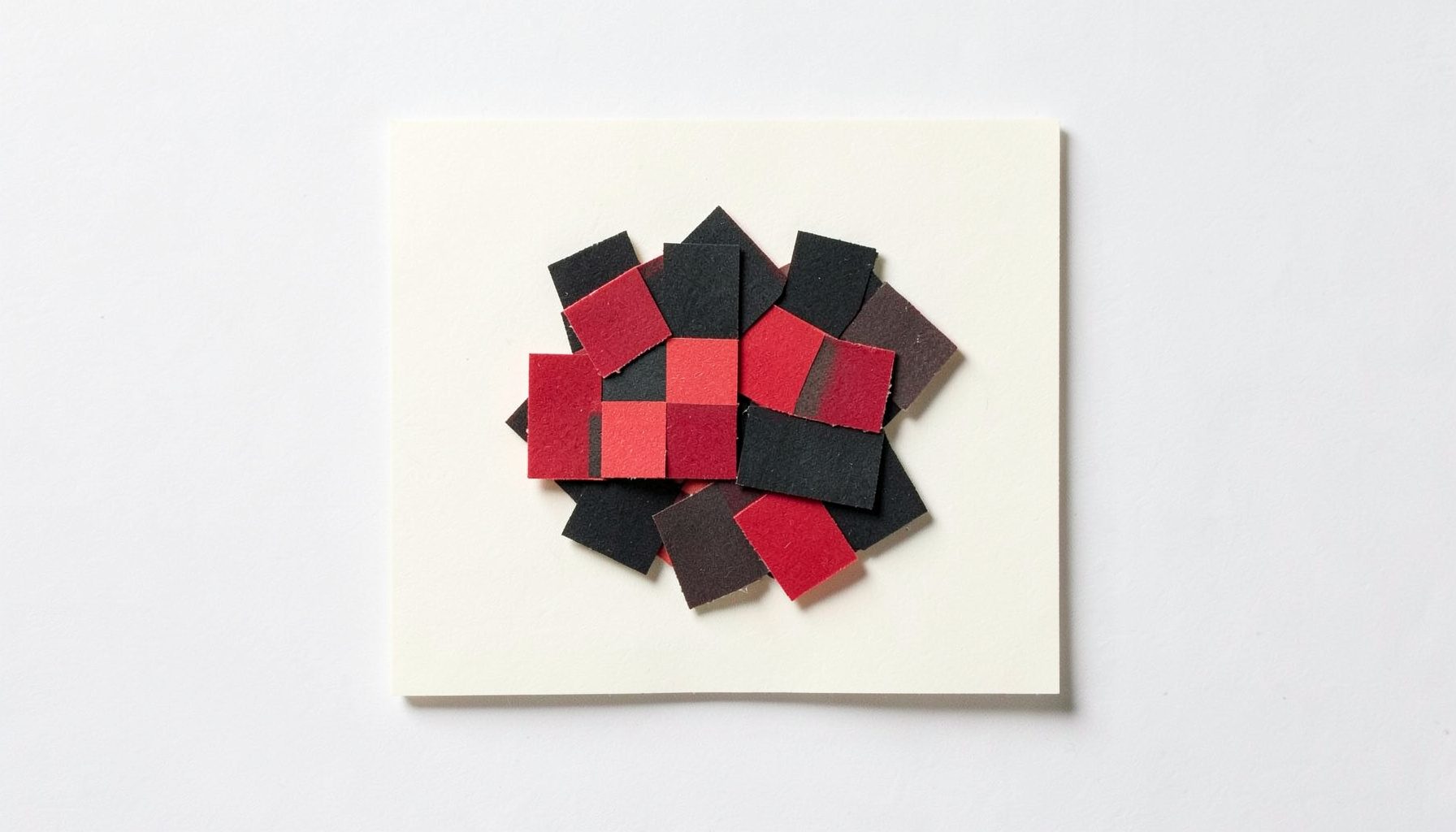 A small layered paper cut-out collage of checker pieces in black and crimson stacked on a cream square, tidy mood