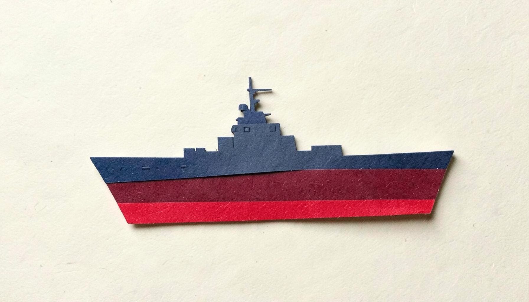 A small layered paper cut-out collage of a battleship silhouette in navy-adjacent gray and red on cream paper, tense mood.